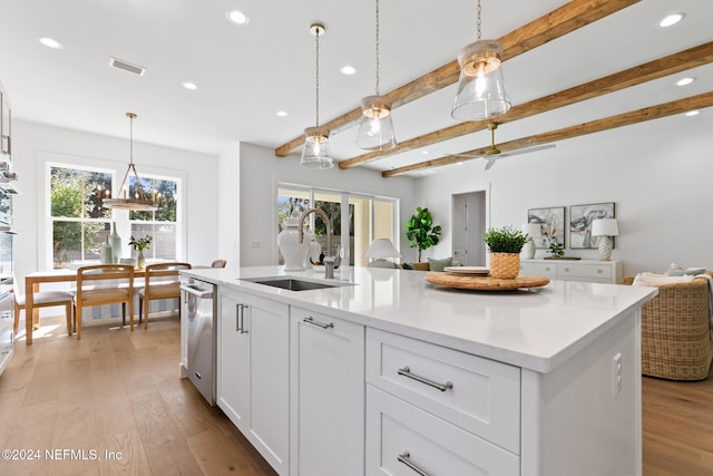 kitchen featuring white cabinets, sink, hanging light fixtures, an island with sink, and beam ceiling