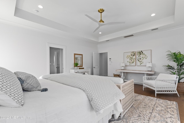 bedroom with dark hardwood / wood-style flooring, a tray ceiling, ceiling fan, and crown molding