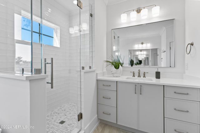 bathroom with crown molding, vanity, and a shower with shower door