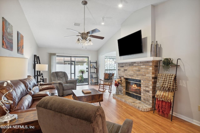 living room featuring a brick fireplace, a textured ceiling, ceiling fan, hardwood / wood-style flooring, and high vaulted ceiling