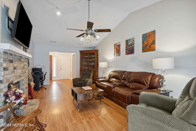 living room featuring ceiling fan, a fireplace, light hardwood / wood-style floors, and vaulted ceiling