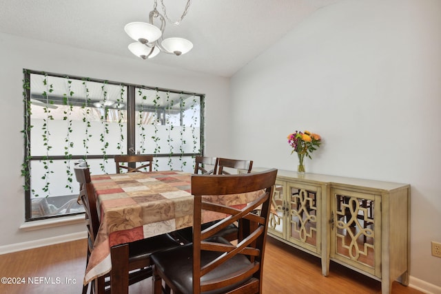 dining room with a healthy amount of sunlight, wood-type flooring, and an inviting chandelier