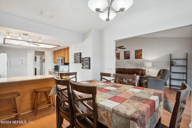 dining space with light hardwood / wood-style floors and vaulted ceiling