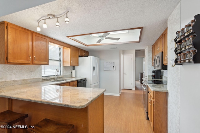 kitchen featuring ceiling fan, sink, stainless steel appliances, kitchen peninsula, and a textured ceiling