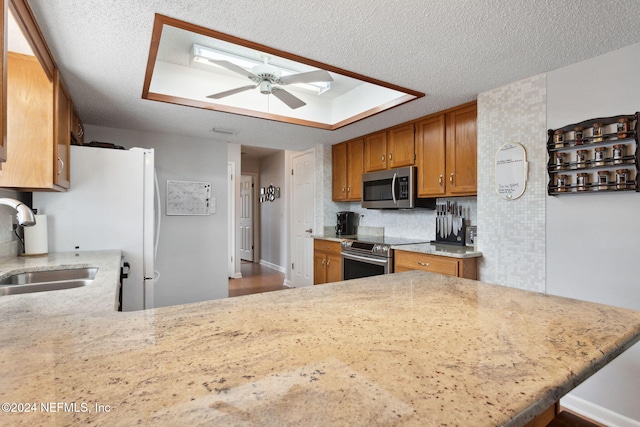 kitchen featuring kitchen peninsula, a textured ceiling, stainless steel appliances, ceiling fan, and sink