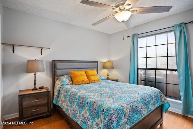 bedroom featuring ceiling fan, a textured ceiling, and light wood-type flooring