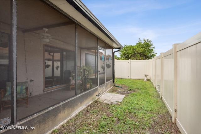 view of yard featuring a sunroom and ceiling fan