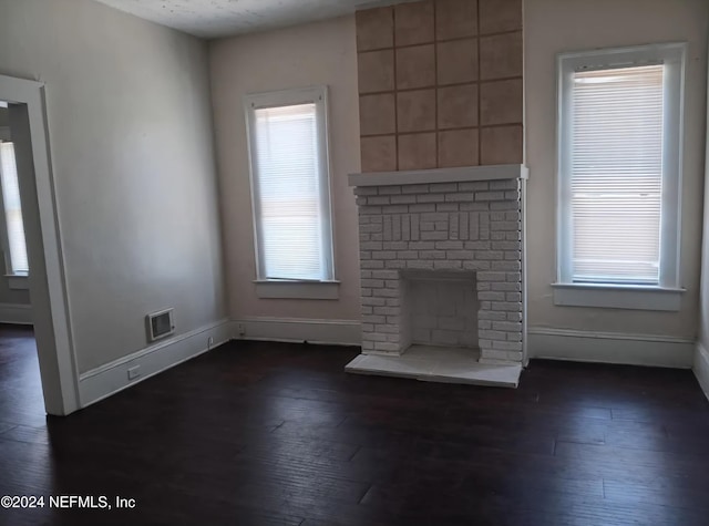 unfurnished living room with dark hardwood / wood-style floors and a brick fireplace