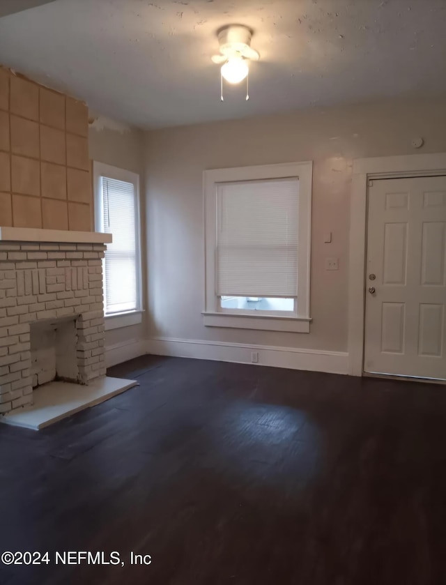 unfurnished living room featuring wood-type flooring and a brick fireplace