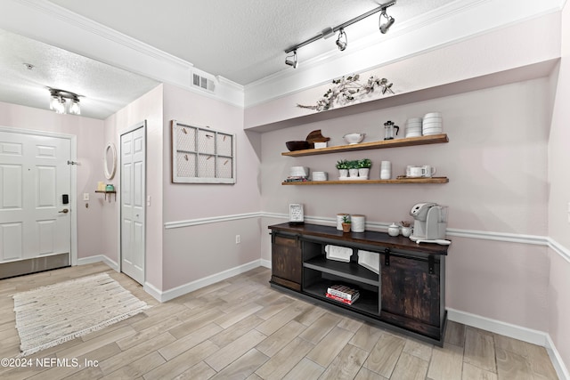 entrance foyer featuring light wood-type flooring, a textured ceiling, and ornamental molding