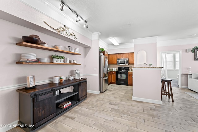 kitchen with a kitchen breakfast bar, rail lighting, ornamental molding, stainless steel appliances, and light hardwood / wood-style flooring