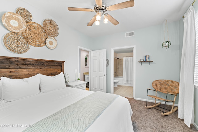 bedroom featuring ceiling fan, ensuite bathroom, and light colored carpet