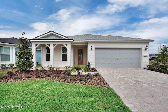 view of front of property with decorative driveway, a front yard, roof with shingles, and an attached garage