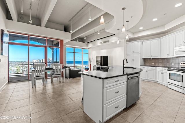 kitchen with a kitchen island with sink, sink, tasteful backsplash, white cabinetry, and stainless steel appliances