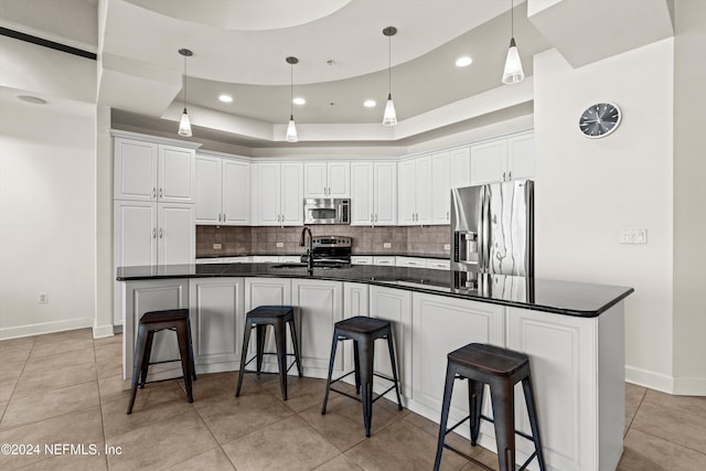 kitchen with stainless steel appliances, white cabinetry, and a center island with sink