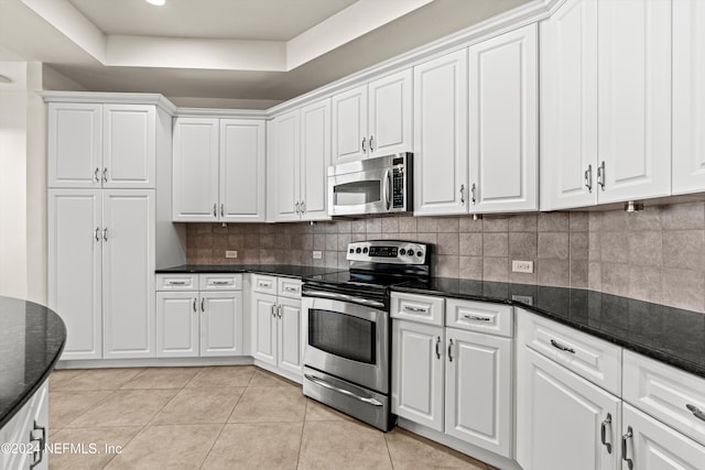 kitchen featuring a raised ceiling, decorative backsplash, white cabinetry, and appliances with stainless steel finishes