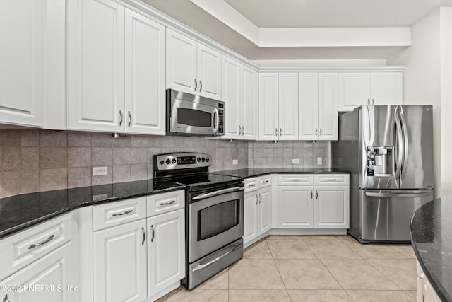 kitchen featuring tasteful backsplash, white cabinets, dark stone counters, and appliances with stainless steel finishes