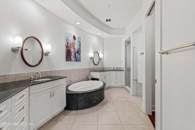 bathroom with tile patterned flooring, vanity, and tiled tub