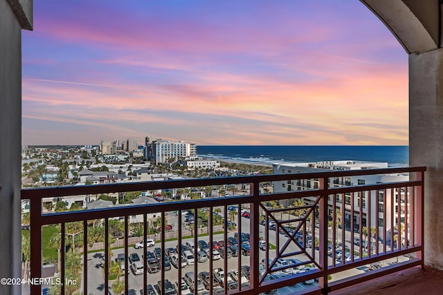 balcony at dusk featuring a water view