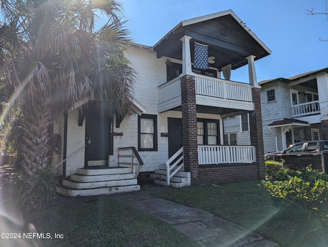 view of front facade with a porch, a balcony, and a front yard