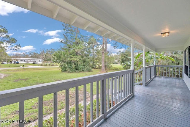 wooden deck featuring covered porch and a lawn