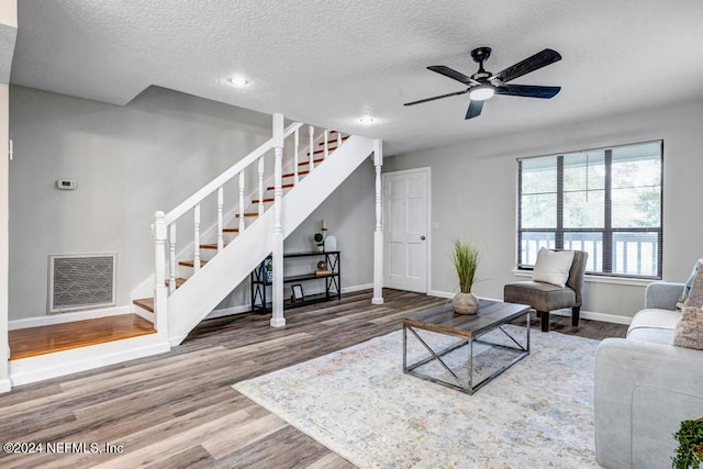 living room with hardwood / wood-style floors, a textured ceiling, and ceiling fan