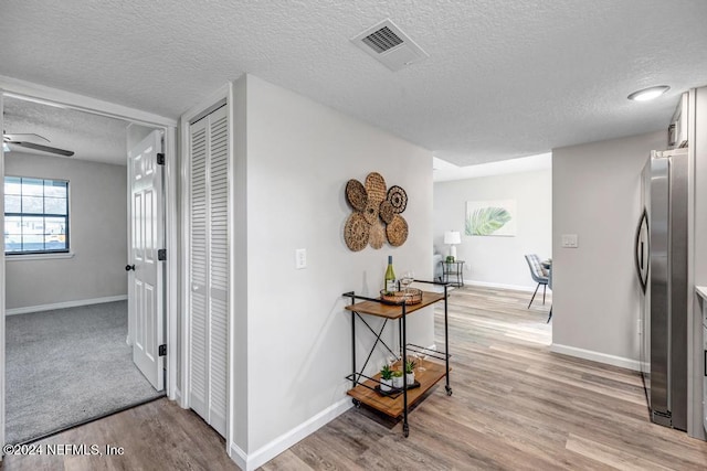 hallway featuring light wood-type flooring and a textured ceiling