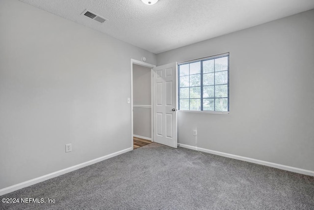 unfurnished room with carpet floors and a textured ceiling