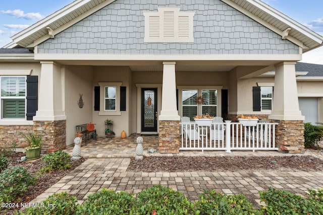 view of front of property featuring stone siding, covered porch, and stucco siding