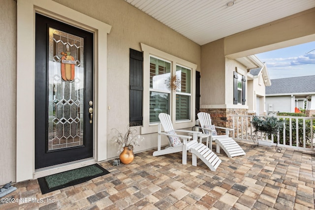 entrance to property featuring covered porch, stone siding, and stucco siding