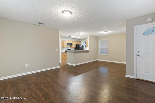 unfurnished living room featuring plenty of natural light, dark wood-type flooring, and a textured ceiling