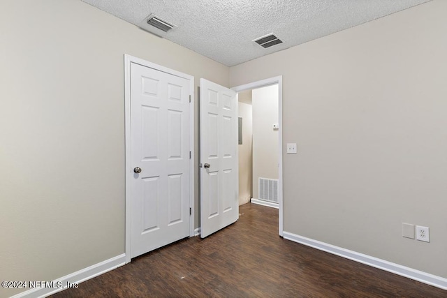 unfurnished bedroom with dark hardwood / wood-style flooring and a textured ceiling