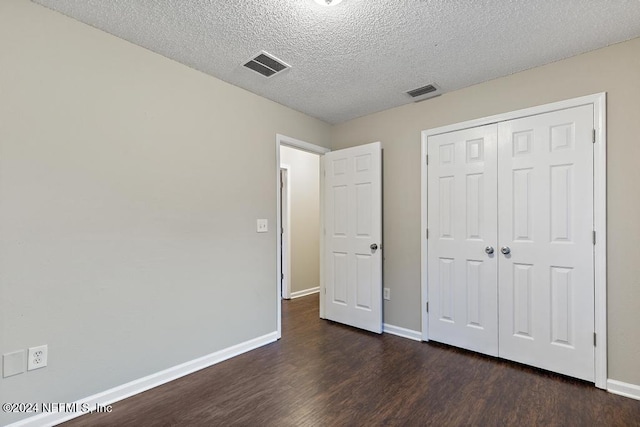 unfurnished bedroom with a closet, dark hardwood / wood-style floors, and a textured ceiling