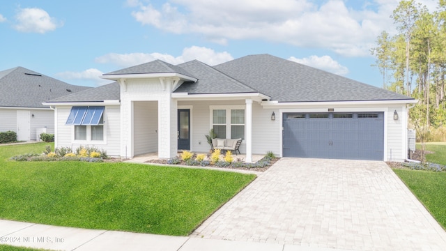 view of front of house with covered porch, a garage, and a front lawn