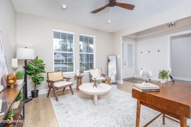 living area featuring ceiling fan, light hardwood / wood-style floors, and a textured ceiling