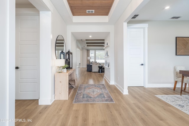 foyer with a raised ceiling and light wood-type flooring