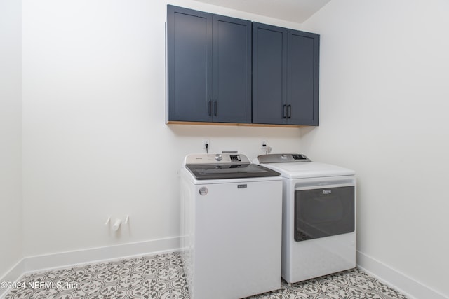 clothes washing area with washer and clothes dryer and cabinets