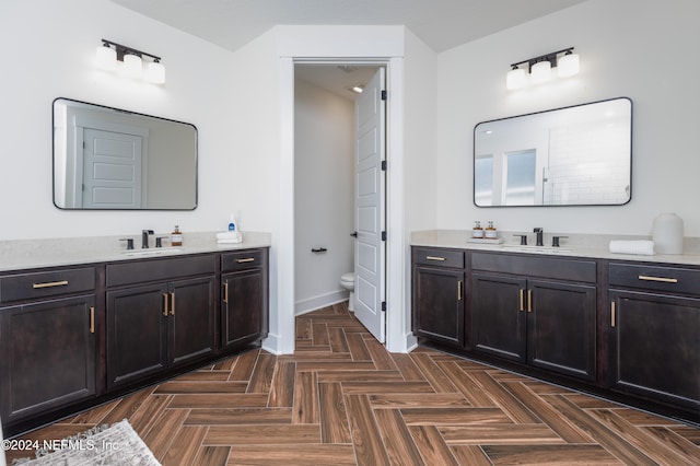 bathroom with vanity, toilet, and parquet floors