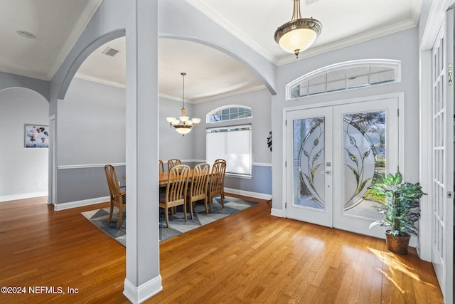 foyer entrance with a notable chandelier, wood-type flooring, ornamental molding, and french doors