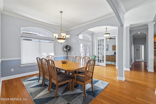 dining area with french doors, ornamental molding, ceiling fan with notable chandelier, and hardwood / wood-style flooring