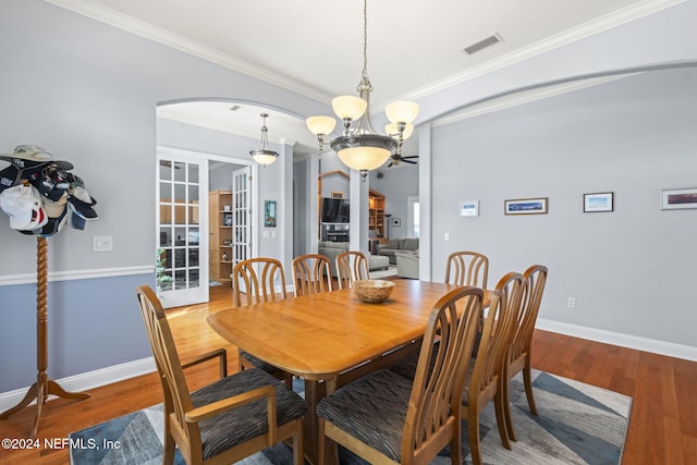 dining area featuring hardwood / wood-style floors, ceiling fan with notable chandelier, french doors, and crown molding