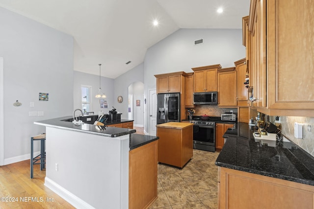 kitchen featuring pendant lighting, light hardwood / wood-style flooring, appliances with stainless steel finishes, tasteful backsplash, and a kitchen island