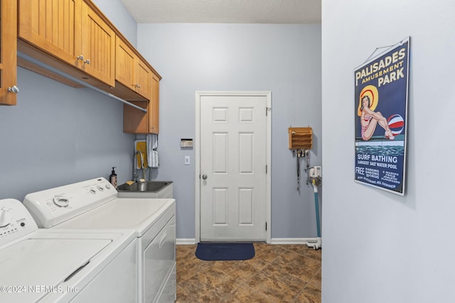 laundry area with washer and clothes dryer, cabinets, sink, and a textured ceiling