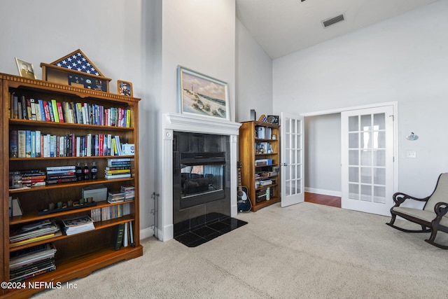 living area featuring a fireplace, high vaulted ceiling, light colored carpet, and french doors