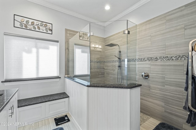 bathroom with vanity, a tile shower, and ornamental molding