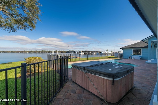 exterior space with a patio, a water view, a hot tub, and a lawn