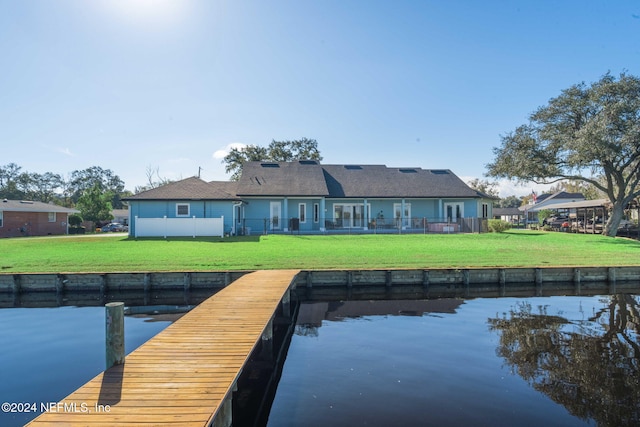 back of house with a lawn and a water view