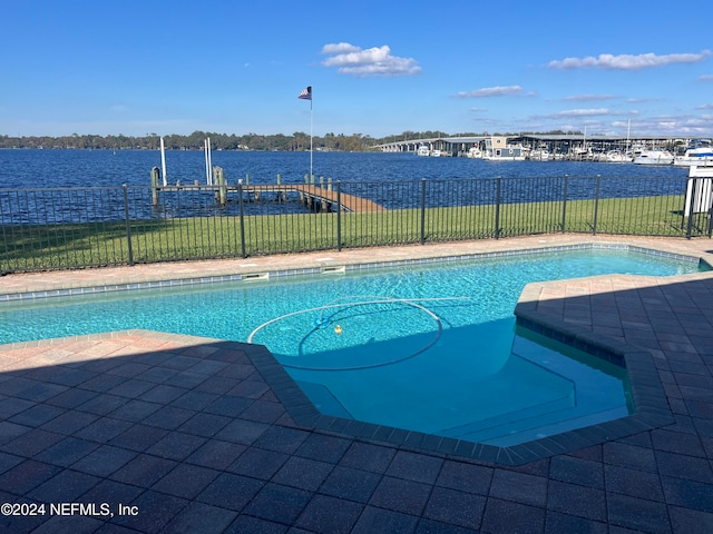 view of pool featuring a water view, a dock, and a patio area