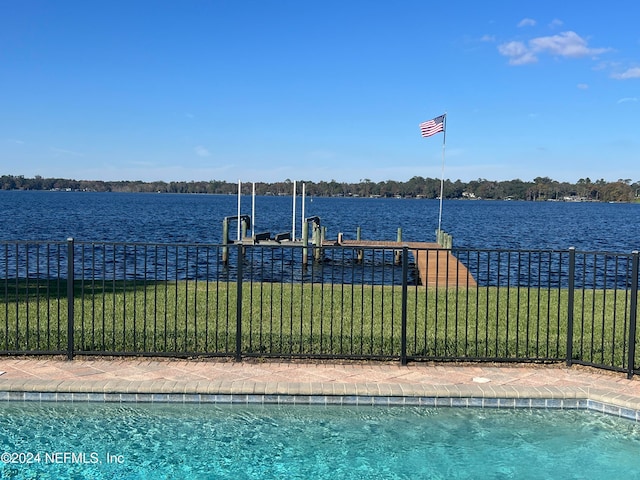 view of swimming pool featuring a lawn, a boat dock, and a water view