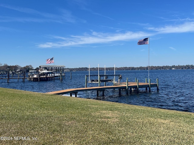 view of dock featuring a lawn and a water view